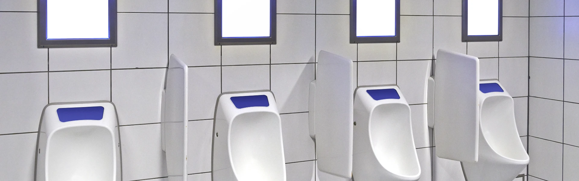 four waterless urinals on bathroom wall